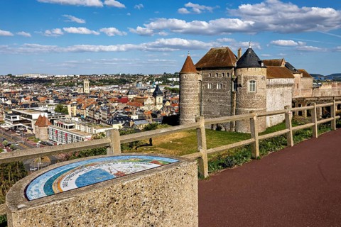Castle with city view in the background, under a blue sky with white clouds, wide view of the city