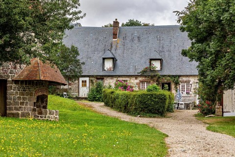 Idyllic farmhouse with garden and gravel path surrounded by green meadows, the historic mill
