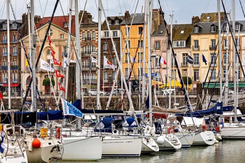 Sailing boats at a lively town harbour with colourful buildings and flags, The harbour of Dieppe in