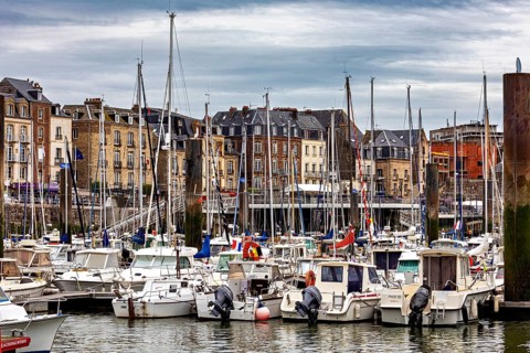 Lively harbour with numerous sailing and motor boats against a backdrop of historic buildings, the