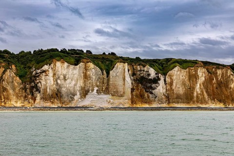 Imposing rocks on the coast with calm sea and cloudy sky, The coast of Dieppe in Normandy, France
