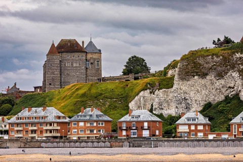 Historic castle on cliffs with modern houses below, under a cloudy sky, sea view, Dieppe Castle in
