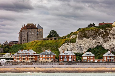 Castle on cliffs above modern buildings, cloudy sky, historic architecture by the sea, Dieppe