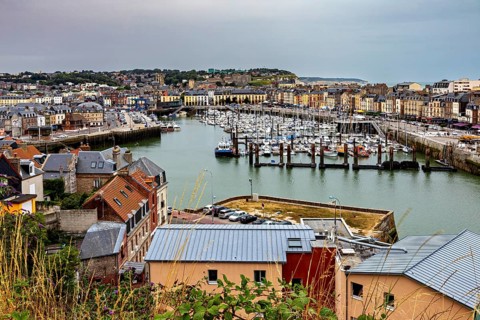 View of a busy harbour town with many boats and city buildings under a cloudy sky, The harbour of