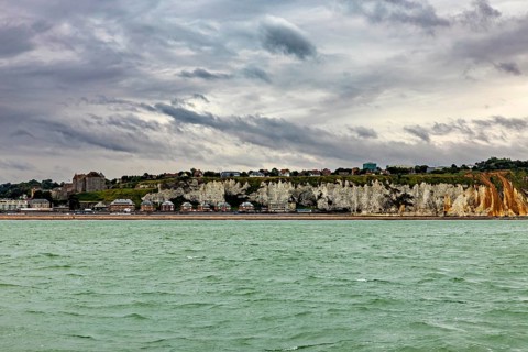 Rocky coast with houses above, under a cloudy sky, The coast of Dieppe in Normandy, France