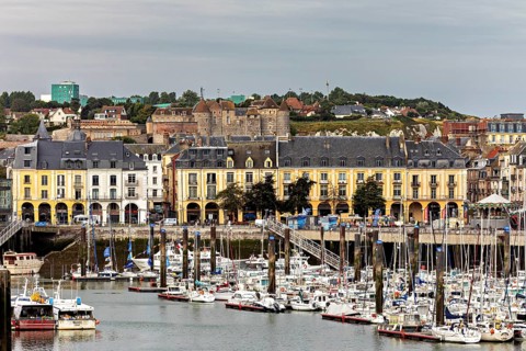 Yellow historic buildings overlook a busy harbour with many boats, The harbour of Dieppe in