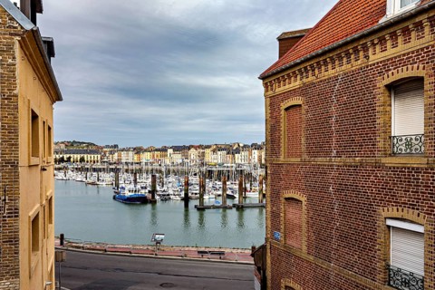View of a harbour with boats through two brick buildings in the foreground, The harbour of Dieppe