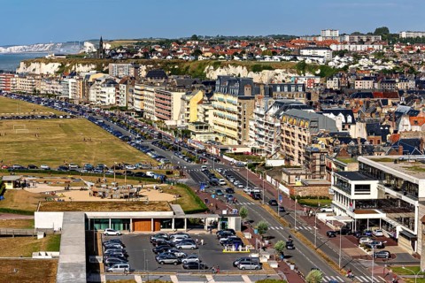 Coastal town with promenade along residential buildings and view of cliffs and sea, The town of