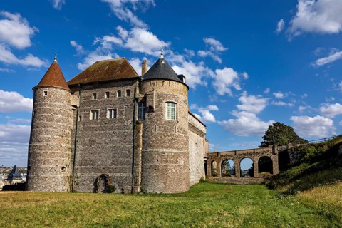 Medieval castle with round towers and stone walls under a blue sky on a green meadow, Dieppe Castle