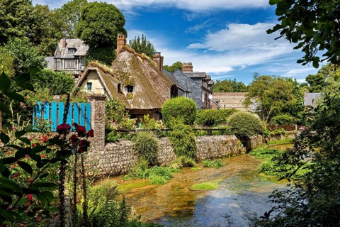 Picturesque village with half-timbered houses and thatched roofs, surrounded by lush nature and a