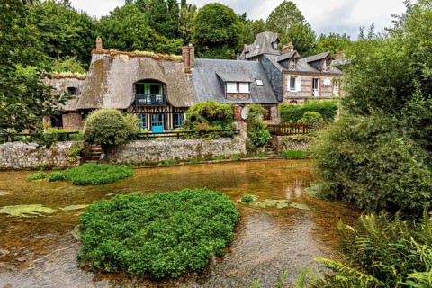 Idyllic river landscape with half-timbered house and lush gardens in the background, the historic