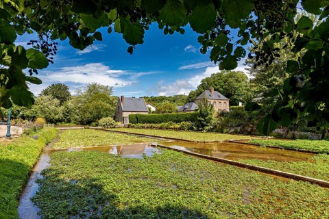 Green fields and brick houses under a clear sky with fleecy clouds, radiating rural tranquillity,