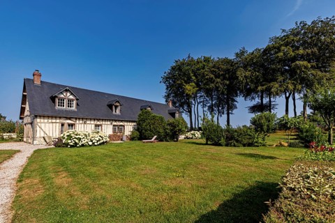 Inviting half-timbered house on a sunny day with a well-tended garden and stately trees, Historic