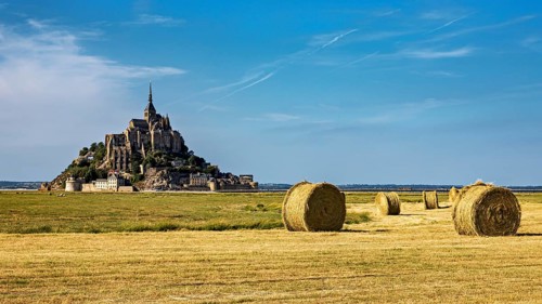 View of Mont Saint-Michel with bales of straw in a field under a clear sky, Mont Saint Michel in