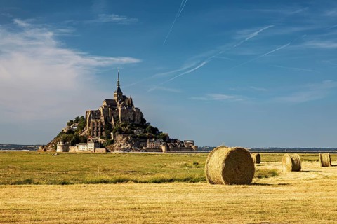 Landscape with Mont Saint-Michel and straw bales under a bright blue sky, Mont Saint Michel in