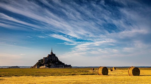 Mont Saint-Michel with cloud formations over a golden field, Mont Saint Michel in Normandy, France