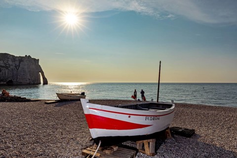 Tranquil beach scene at sunset with boat and people near cliffs, rowing boat at sunset on the coast