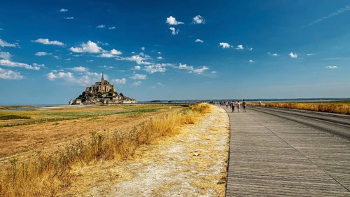 The monastery of Mont Saint-Michel in the distance under a clear sky and slightly cloudy, Mont
