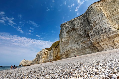 Pebble beach in front of high cliffs with blue sky and sea, The cliffs and alabaster coast of