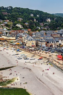 Beach scene in a coastal town with many people and boats, Etretat in Normandy, France