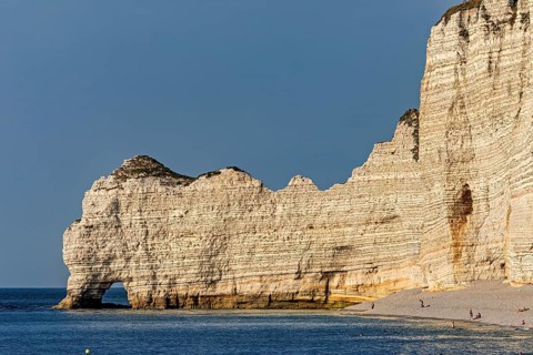 High cliffs form the coastline, overlooking a calm beach with clear skies, The cliffs and alabaster