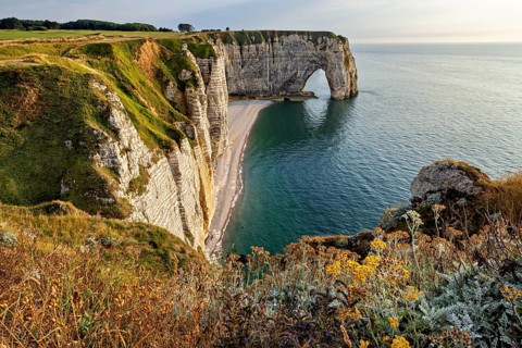 High cliffs with an impressive rock arch, surrounded by green vegetation, The cliffs and alabaster