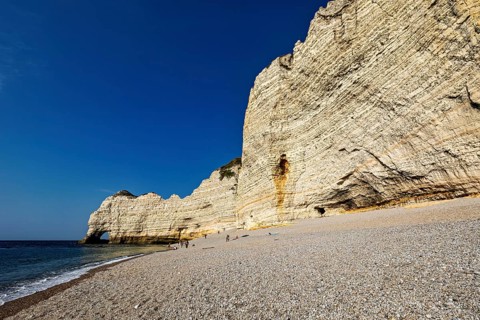 Large white rocks lining a pebble beach against the blue sky and sea, The cliffs and alabaster