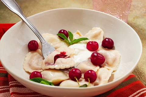 Traditional dumplings with cherries and yogurt, close-up, no people