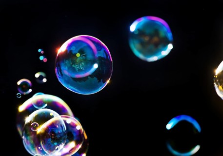 Iridescent soap bubbles in the colours of the rainbow against a black background, Recklinghausen,