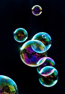 Iridescent soap bubbles in the colours of the rainbow against a black background, Recklinghausen,