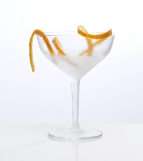 Frosted empty cocktail glass with orange zest as garnish against a white background, studio shot