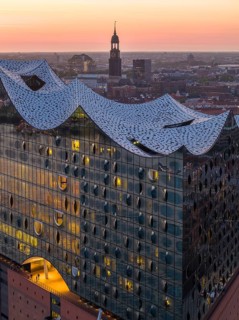 Aerial view of the Elbphilharmonie at sunset with illuminated windows and view over Hamburg and the