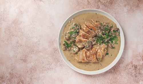 Chicken in cream sauce with mushrooms, on a plate, no people