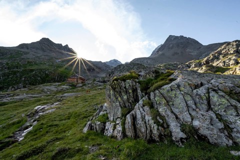 Mountain hut Elberfelderhütte in front of a rocky mountain landscape, sun star in the morning, in