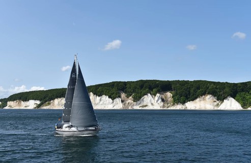 Sailing boat passes the chalk coast of Rügen, Mecklenburg-Vorpommern, Germany
