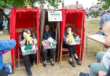 Three women forming human fruit machine game at village summer fete, Bawdsey, Suffolk, England, UK