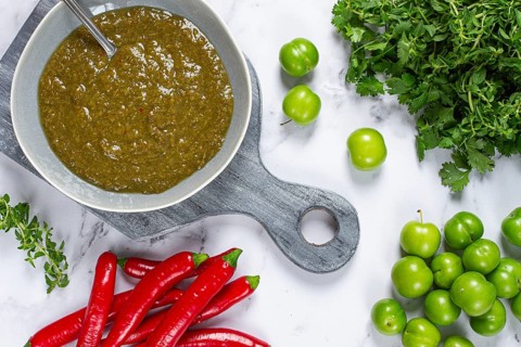 Tkemali sauce, made from green cherry plum, with ingredients on the table, top view, Georgian