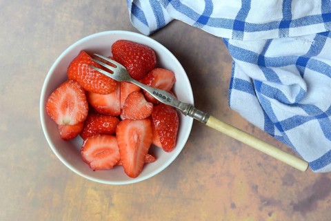 Sliced strawberries in hull with fork, Fragaria