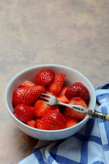 Sliced strawberries in hull with fork, Fragaria