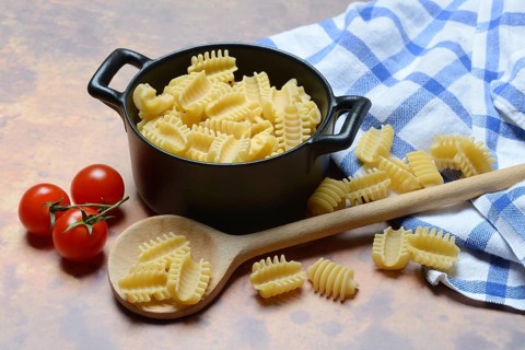 Italian pasta, Radiatori variety, in pots and wooden spoon