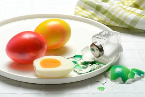 Easter eggs and salt shaker on plate, partially peeled