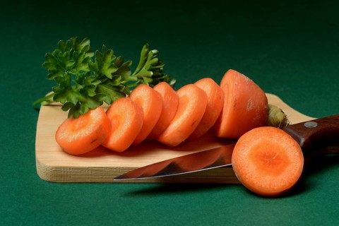 Carrot, carrot slices with kitchen knife on wooden board