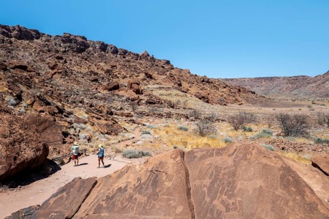 Tourists look at depictions of animals on a rock slab, petroglyphs, rock engravings, Twyfelfontein,