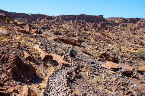 Tourist on a hiking trail, Barren landscape in a valley, Twyfelfontein, Kunene, Namibia