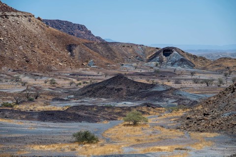 Dry landscape with yellow grass and black volcanic hills, Burnt Mountain, Damaraland, Kunene,