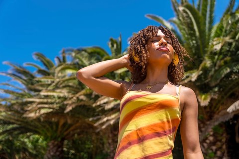 Young woman enjoying music with headphones in a tropical location, embracing the summer vibes and