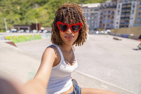 Young woman with heart shaped sunglasses enjoying a sunny day at a skatepark, capturing the moment