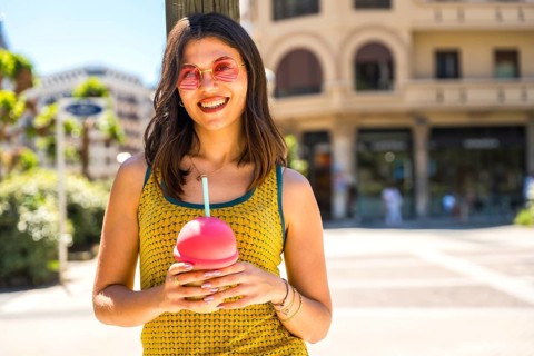 Happy young woman smiling brightly while enjoying a refreshing cold drink on a sunny summer day in