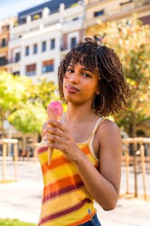 Stylish young woman savoring a refreshing strawberry ice cream cone on a sunny day in the city