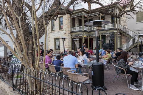 Tourists eating outside on the patio of the Silver Creek Beer Garden in Fredericksburg, Texas, USA